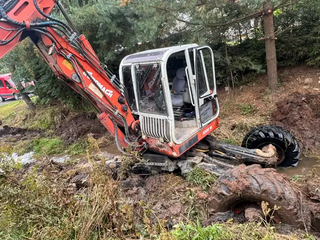 Červený bagr při práci v bahnitém korytě